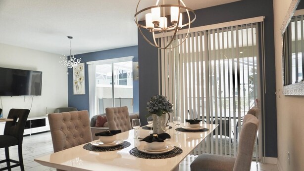A modern dining area with a white table, beige chairs, and a decorative centerpiece. - Elegant 4 Bedroom Getaway w/Private Pool 114 (ChampionsGate)