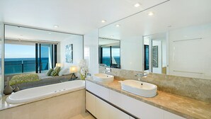 A modern bathroom with two sinks, a large mirror, and a view of the ocean through a sliding door. - Soul Private Apartments (Surfers Paradise)
