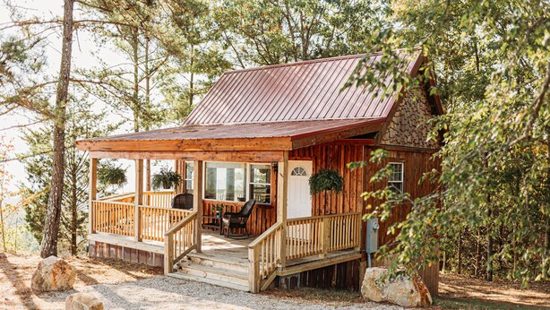 Een rustieke blokhut met een houten terras, een veranda en een stenen fundering.