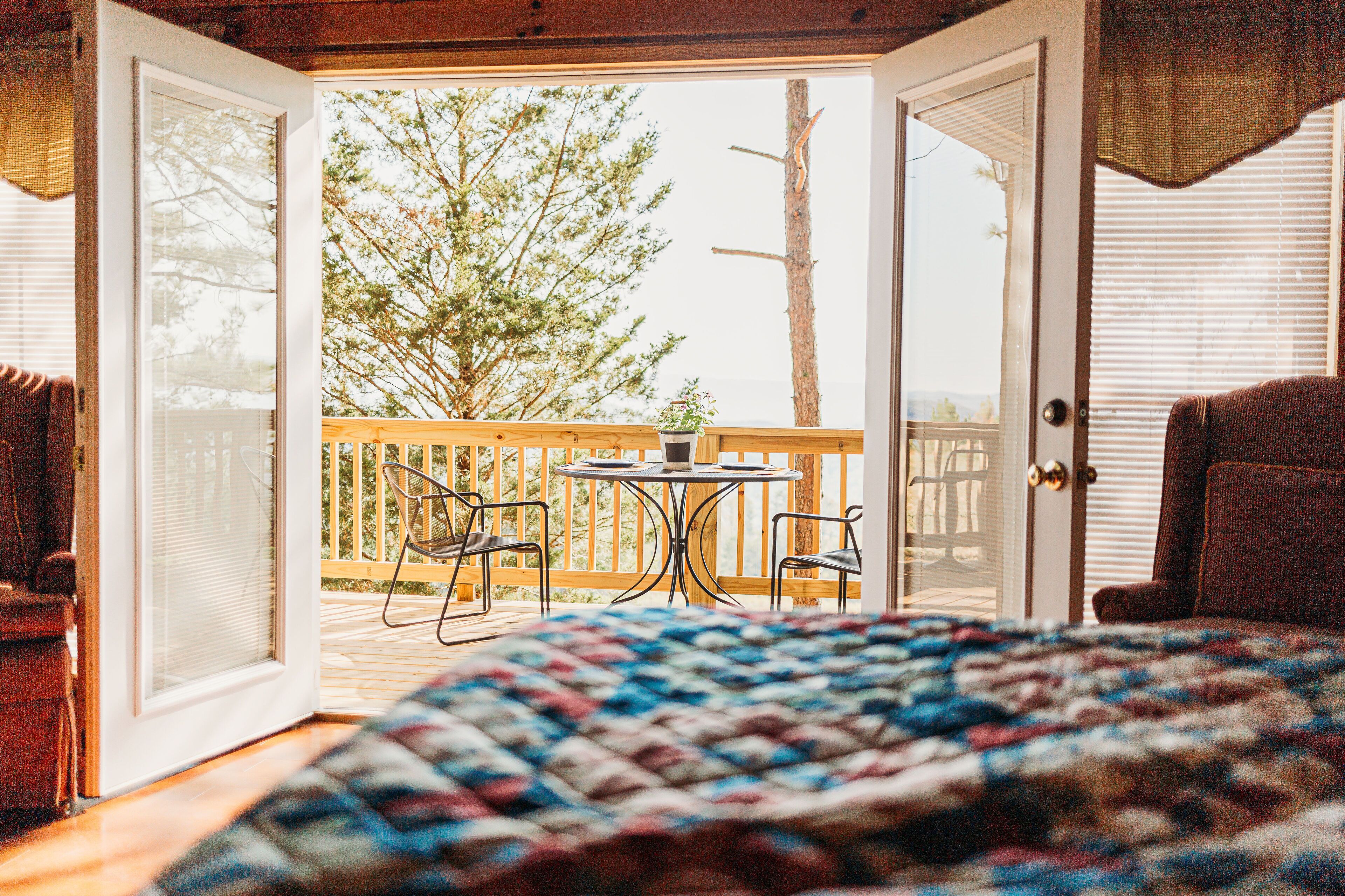 An open bedroom with a view of a deck, a table, and chairs outside.