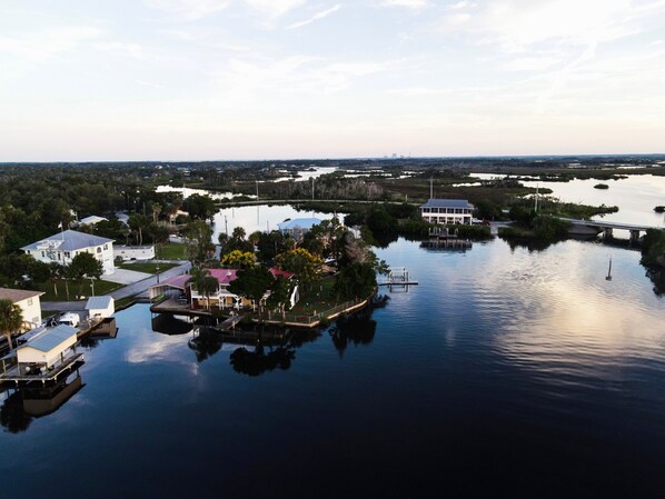 Vue aérienne d’une propriété située au bord de l’eau, avec un quai, une maison et un bateau.