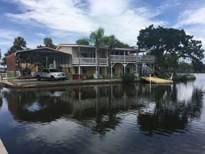 Une propriété située au bord de l’eau, dotée d’un abri-voiture couvert, d’un quai et d’un bâtiment à deux étages avec un balcon.