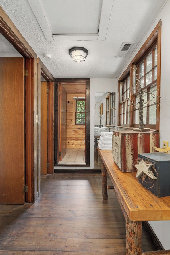 A wooden hallway with a bench, a door, and a window with a view of the outdoors.