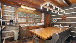A rustic kitchen with wooden cabinets, a large island, and a star decoration on the wall. - MOUNTAIN JOY COTTAGES #5 - STARS AND STRIPES (Maggie Valley)