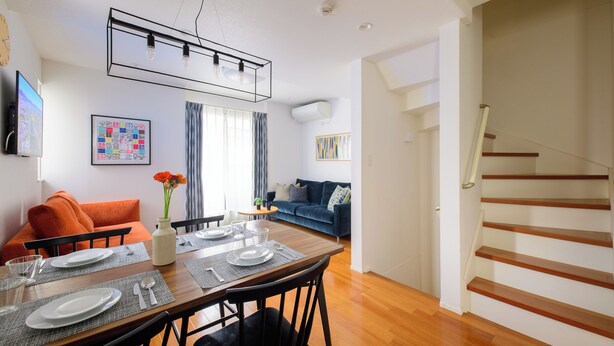 A modern living room with a dining area, a staircase, and a sofa. - Sangen-jaya House-O (Tokyo)