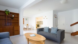 A spacious living room with a grey sofa, a wooden coffee table, and a dining area with a white table and chairs. - Great house with Pool S.Agustín By CanariasGetaway (Maspalomas)