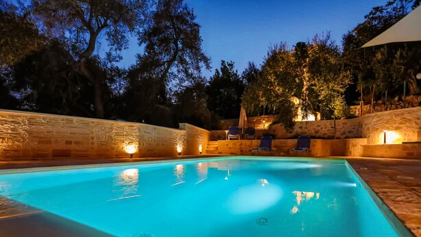 An outdoor swimming pool with stone walls and lounge chairs.