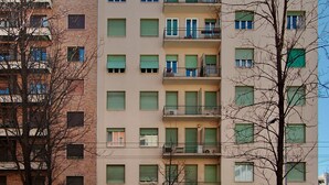 Ein mehrgeschossiges Wohngebäude mit Balkonen, einem Hauseingang und einer sichtbaren Tür.