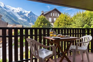A balcony with a table set for breakfast, overlooking a mountain landscape.