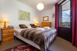 Una habitación de hotel con una cama, dos mesitas de noche, un aparador, una ventana con cortinas, un mapa en la pared y una alfombra.