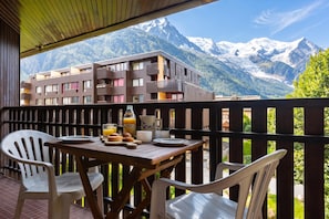Un balcone con tavolo apparecchiato per la colazione, vista su un paesaggio montano.