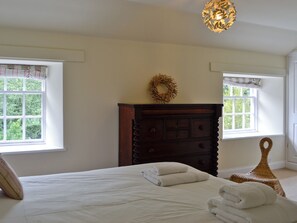 Un dormitorio con cama, cómoda, ventanas y un adorno decorativo.