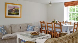 A living room with a sofa, a coffee table, and a dining area with chairs and a table.