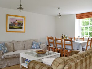 A living room with a sofa, a coffee table, and a dining area with chairs and a table.