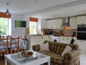 A compact kitchen with a dining area, a washing machine, and a flat-screen TV.