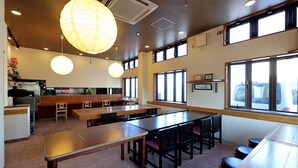A restaurant with high tables, chairs, and hanging paper lanterns. - Tabist Izumi Yusen Shukuhaku Center (Izumi)