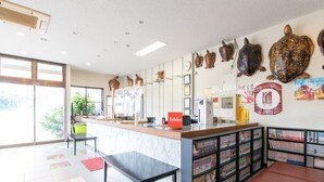A library with a long counter, bookshelves, a red sign, and decorative turtle sculptures. - Tabist Izumi Yusen Shukuhaku Center (Izumi)