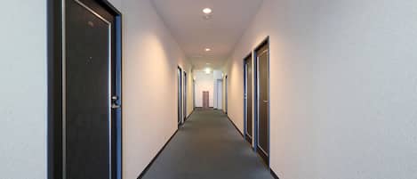 Un pasillo largo y estrecho con puertas a ambos lados, que conduce a habitaciones individuales.