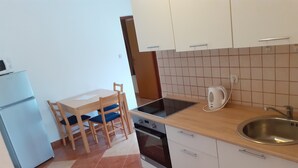 Eine kleine Küche mit Esstisch, Stühlen, Herd, Spüle und Wasserkocher.