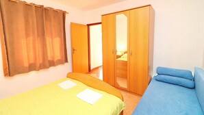 Ein Schlafzimmer mit Bett, Schlafsofa, Kleiderschrank und Vorhang.