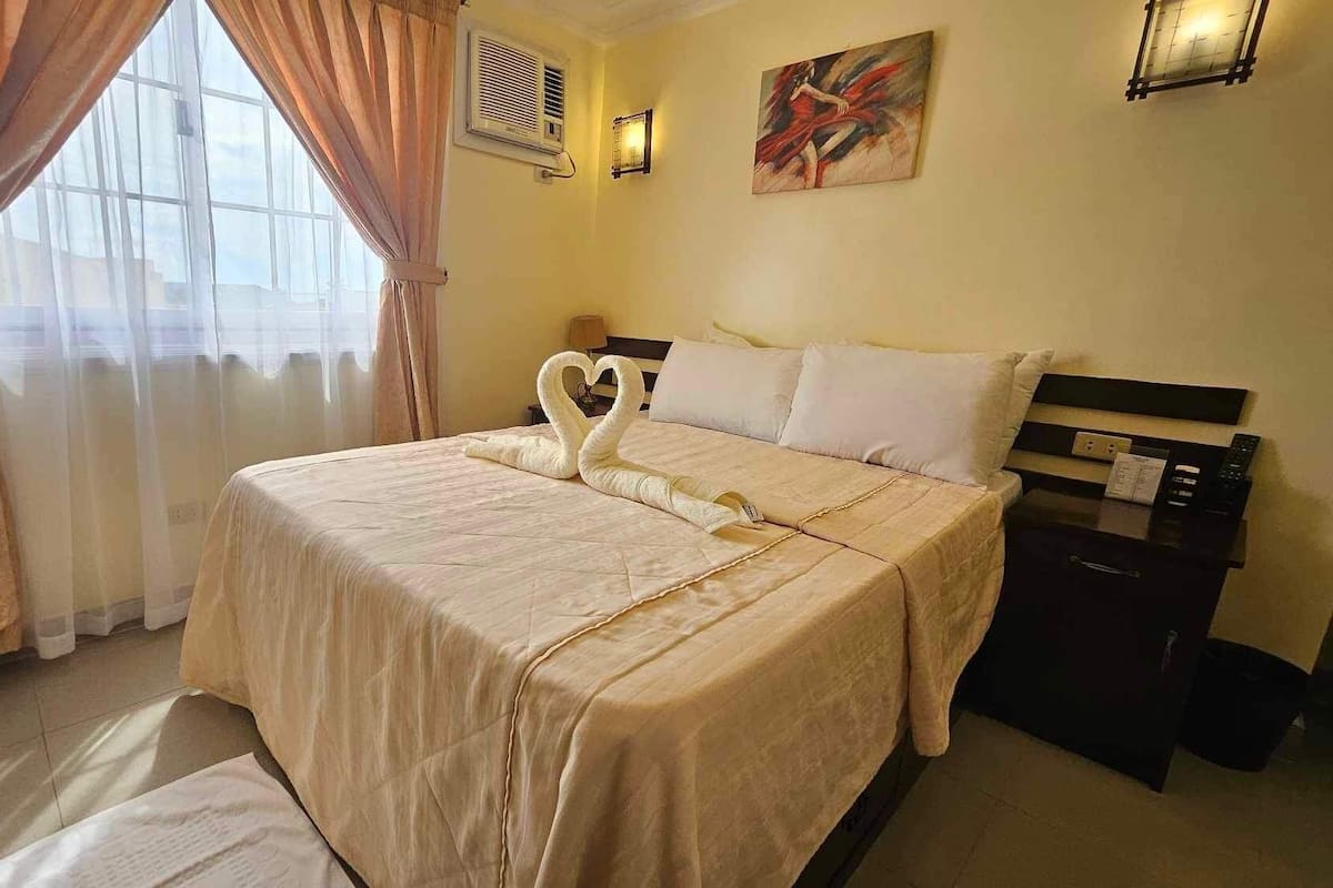 A hotel room with a bed, a nightstand, a lamp, and a painting on the wall.