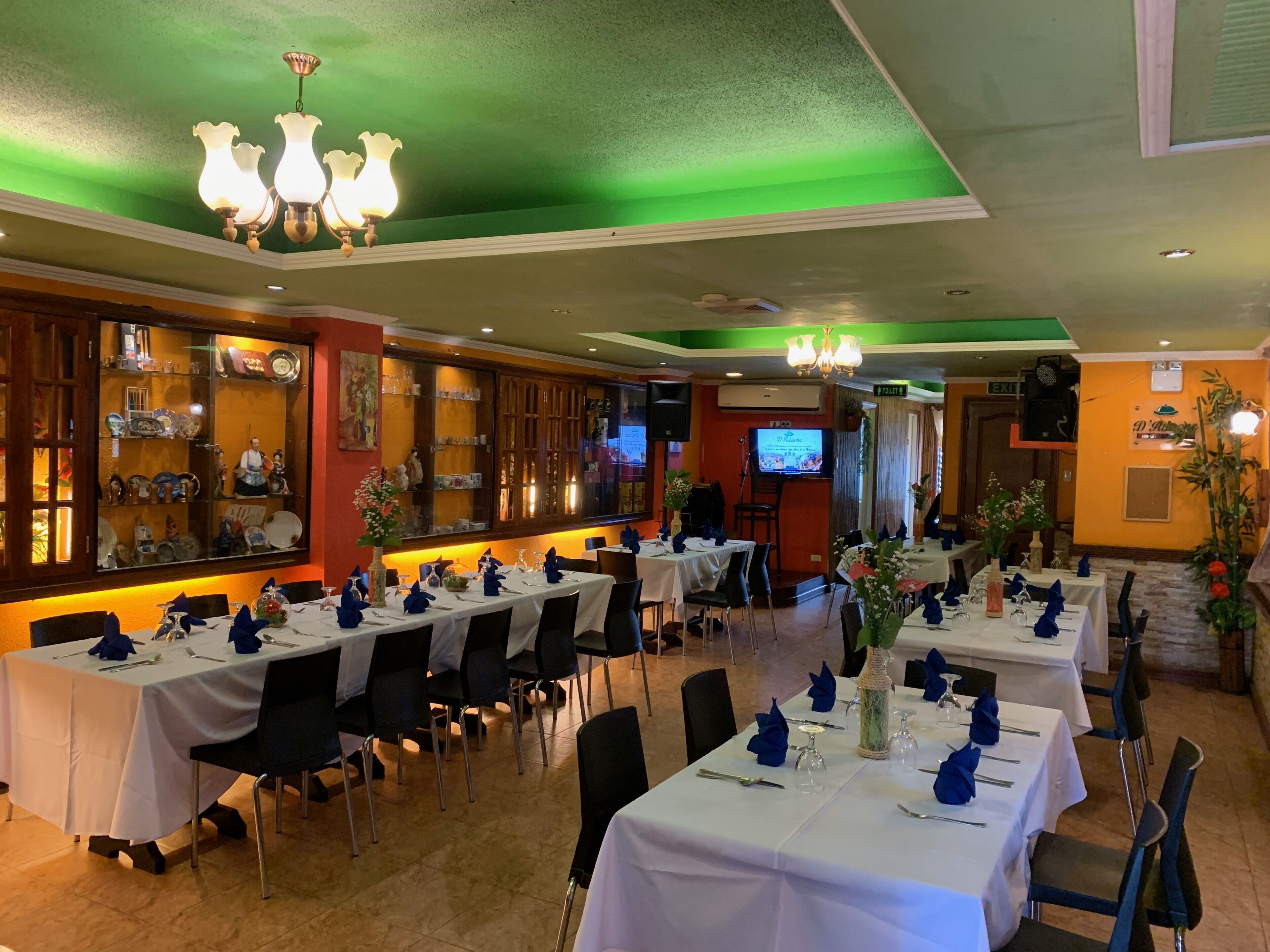 Ein Restaurant mit mehreren Esstischen, einer Bar und einem Fernseher.