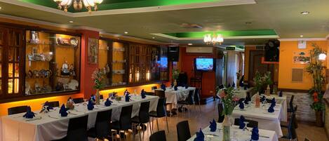 Ein Restaurant mit mehreren Esstischen, einer Bar und einem Fernseher.