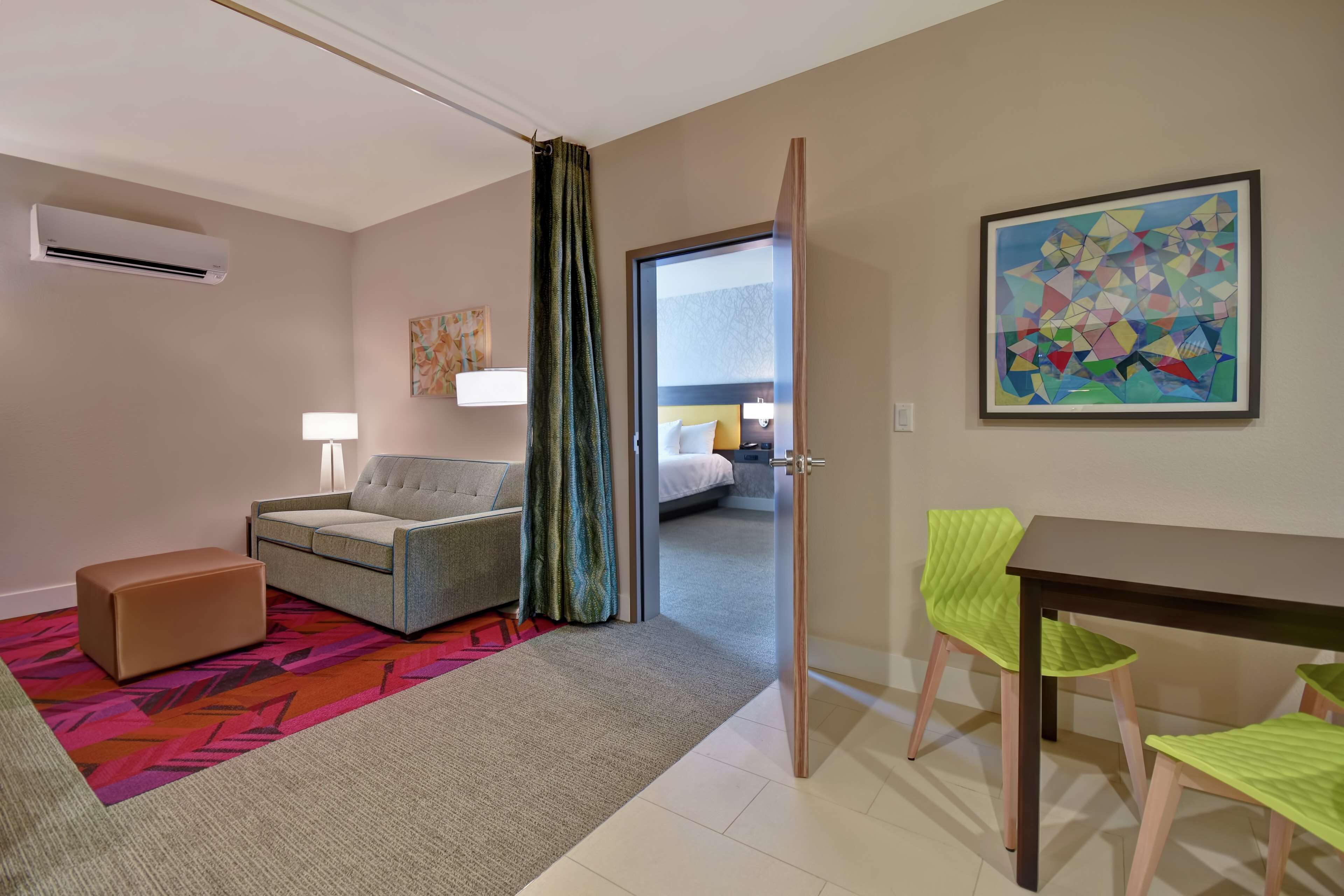 Habitación de hotel con sofá, una pequeña mesa, una silla, una cama y un cuadro en la pared.