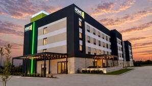 A modern hotel building with a flat roof, multiple windows, and a prominent entrance with outdoor seating. - Home2 Suites by Hilton Wichita Northeast (Wichita)