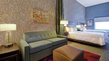 Ein Hotelzimmer mit einem grünen Sofa, einem Bett mit weißen Laken, einem Nachttisch mit Lampe und einem farbenfrohen Teppich.