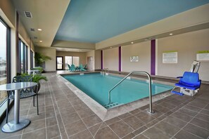 An indoor swimming pool with a pool lift, chairs, and tables. - Home2 Suites by Hilton Wichita Northeast (Wichita)