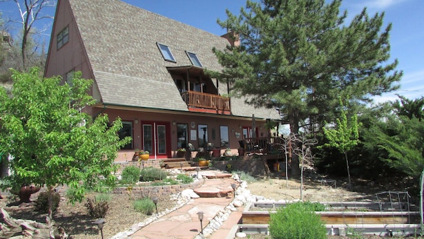 A two-story house with a sloped roof, a balcony, and a stone pathway leading to the entrance. - High Desert Perch with views. (Farmington)