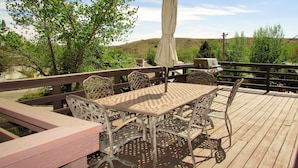 A wooden deck with a table and chairs, an umbrella, and a grill. - High Desert Perch with views. (Farmington)