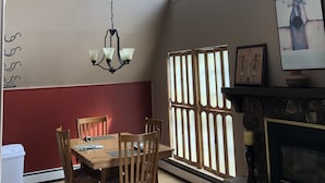 A dining area with a wooden table and chairs, a chandelier, and a fireplace. - High Desert Perch with views. (Farmington)