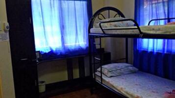 A bunk bed room with a desk and chair, a window with curtains, and a tiled floor.