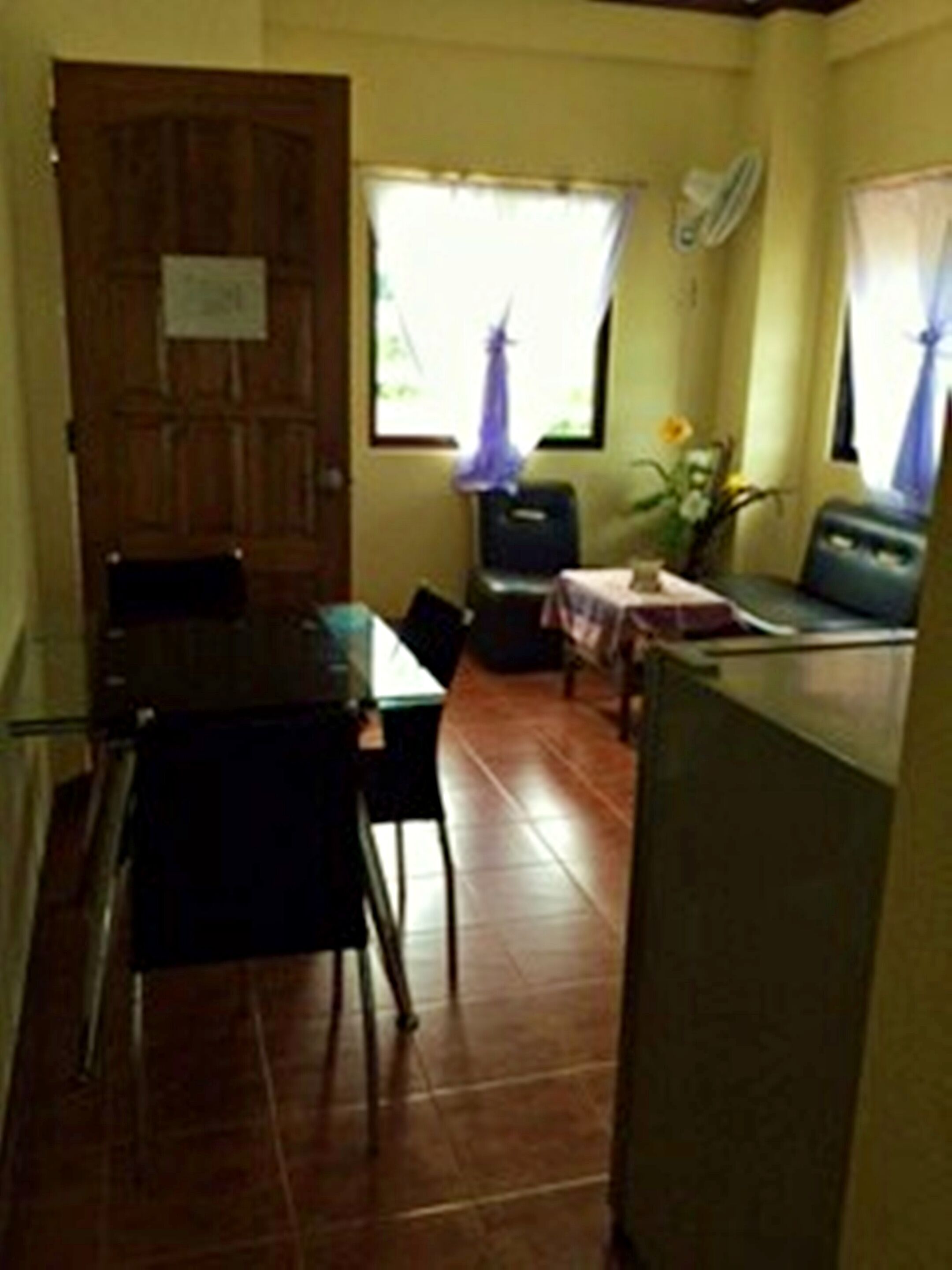 A compact kitchen with a dining table, chairs, and a refrigerator.