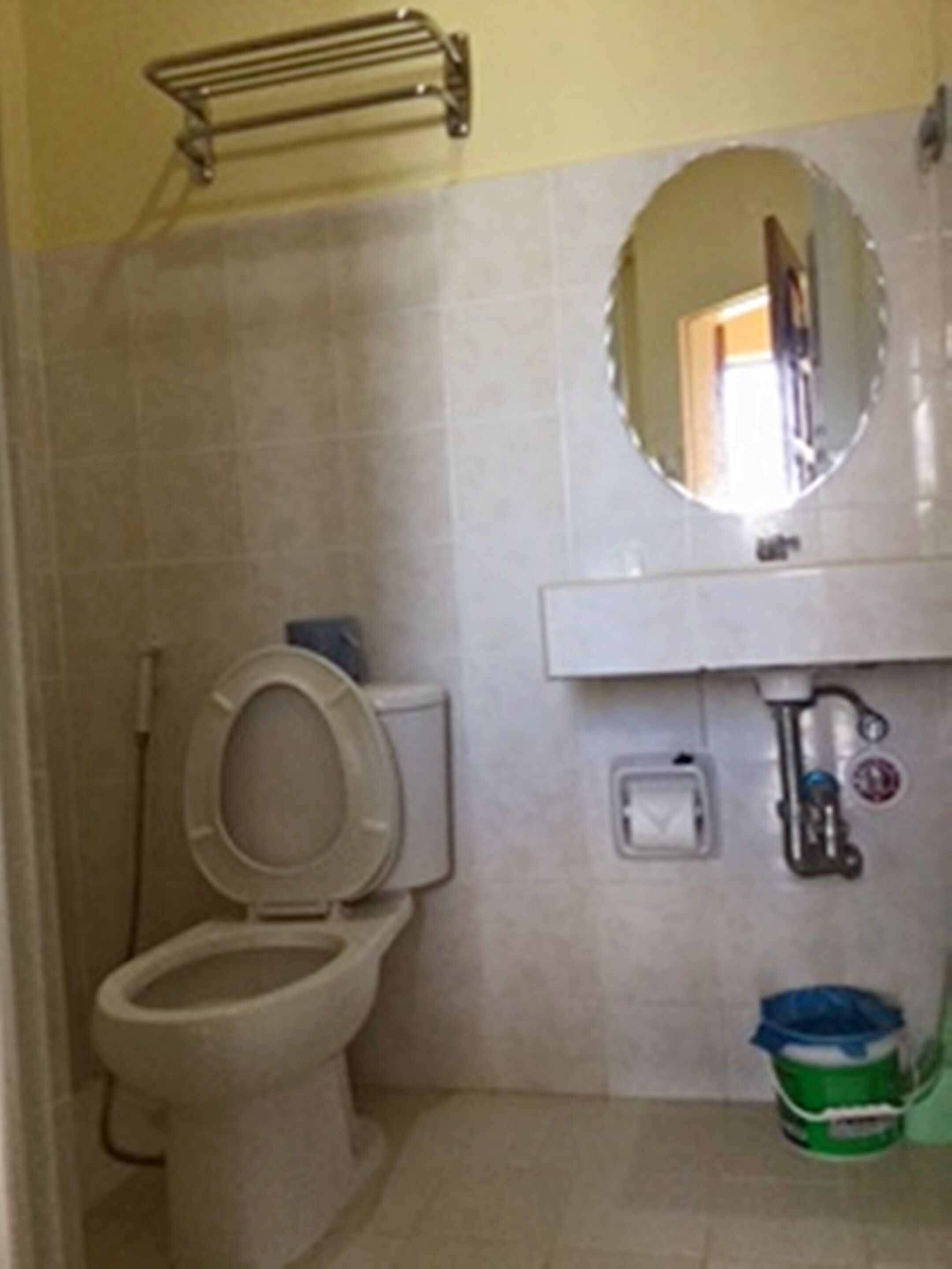 Un baño con inodoro, lavamanos y espejo.