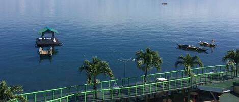 Hotel aan het water met een zwembad, een klein steiger en uitzicht op zee en bergen.
