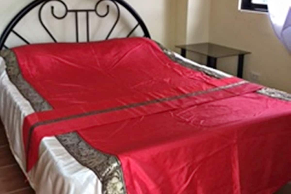 A room with a bed, a small table, and a window with curtains.
