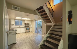 A modern kitchen with a central island, built-in appliances, and a sliding glass door leading to a patio.