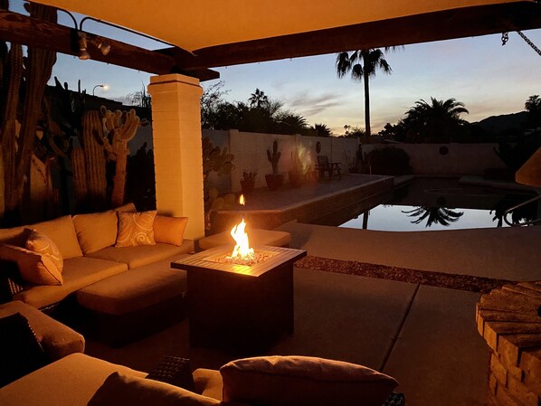 An outdoor seating area with a fire pit, a pool, and cacti.