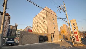 A modern building with a geometric facade, a visible entrance, and a sign indicating a motel. - 7 Motel (Gimhae)