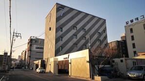 A modern building with a distinctive diamond-patterned facade, a visible entrance, and a sign indicating it is a motel. - 7 Motel (Gimhae)