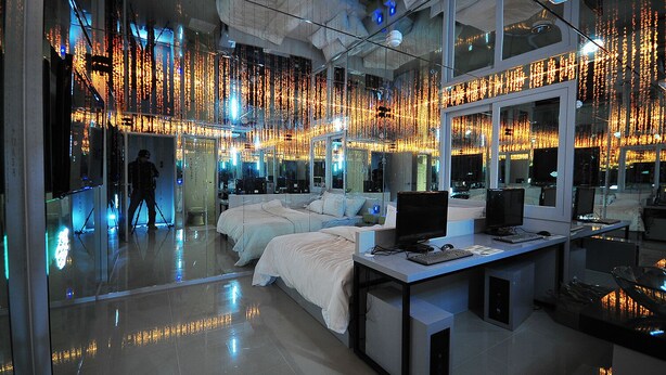 A modern hotel room with a glass wall, a bed, a desk with a computer, and a large mirror. - 7 Motel (Gimhae)