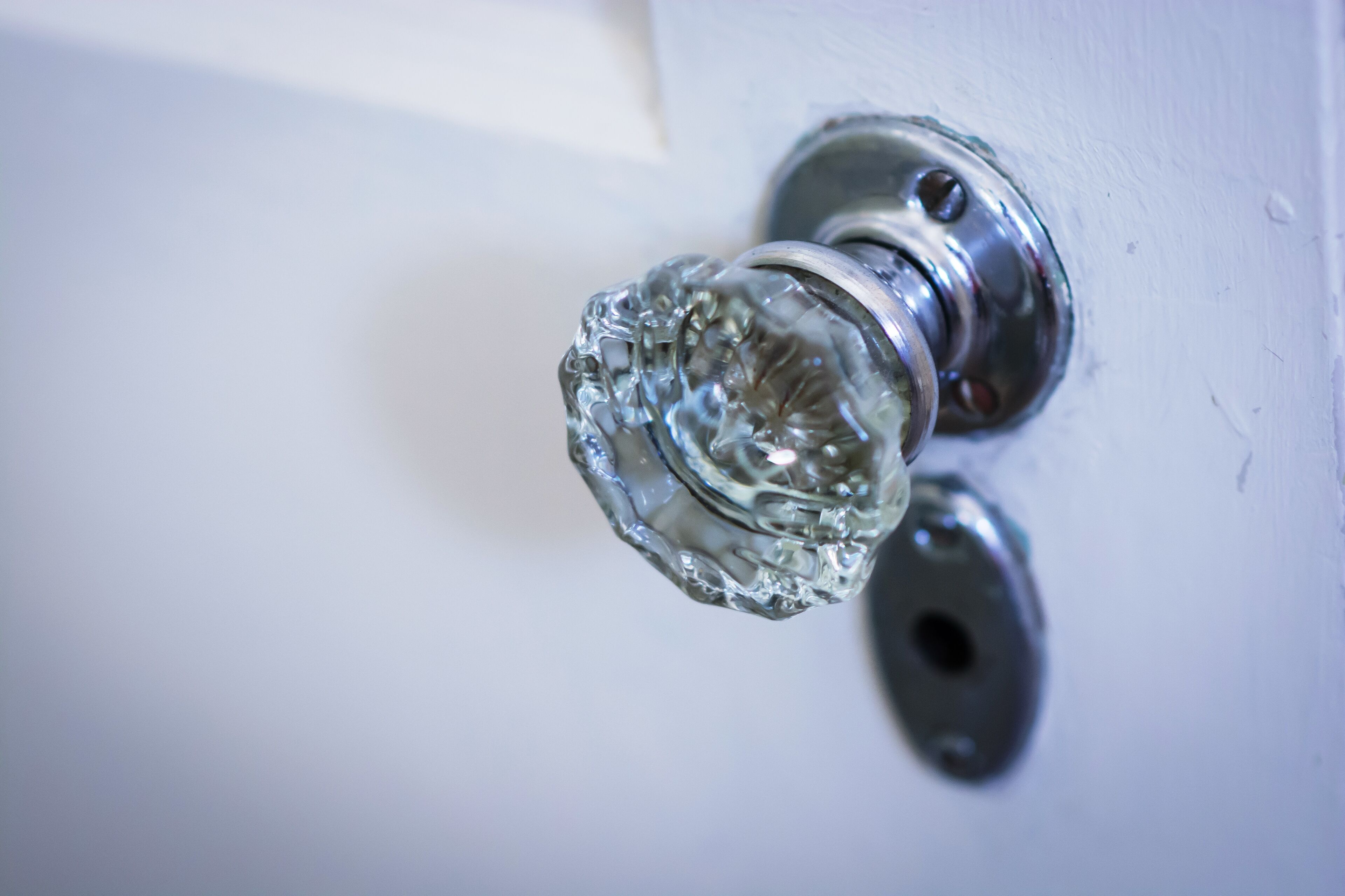 A close-up of a clear glass doorknob on a white door.