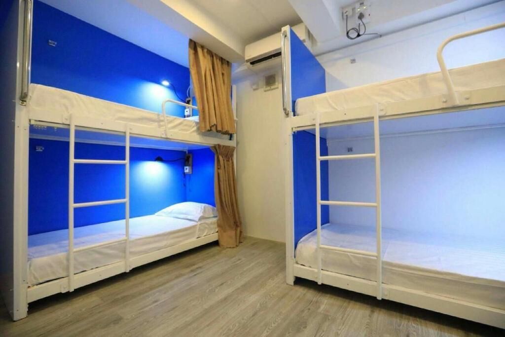 Una habitación con dos literas, suelo de madera y pared azul.