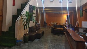 Un hall con escaleras, una zona de estar y un mostrador de recepción.