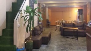 Un vestíbulo de hotel con una escalera, zona de estar y comedor.