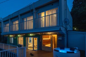 Un edificio de dos pisos con un área de spa, que incluye una bañera de hidromasaje y una sauna.