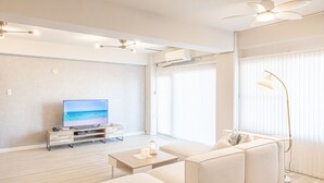 A modern living room with a flat-screen TV, a sofa, a coffee table, and a floor lamp. - Shirahama White Beach House (Shirahama)